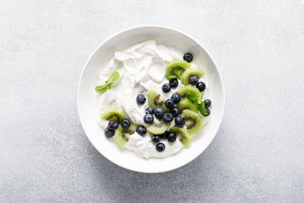 White plain greek yogurt with fresh blueberries and kiwi fruit, top view
