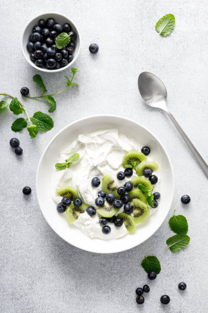 istock White plain greek yogurt with fresh blueberries and kiwi fruit, top view 1990744042