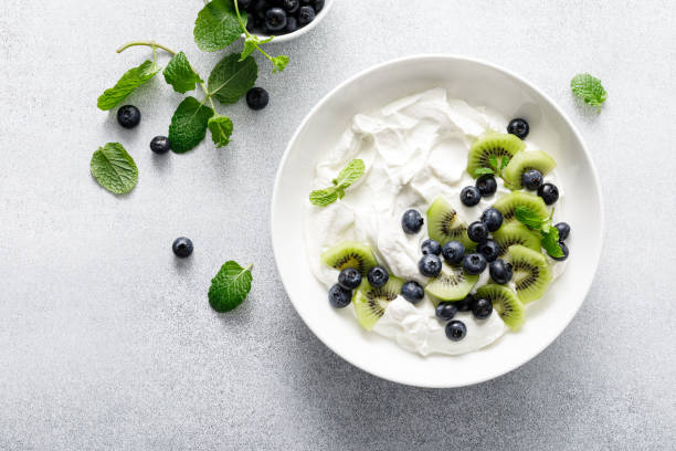 istock White plain greek yogurt with fresh blueberries and kiwi fruit, top view 1990745056