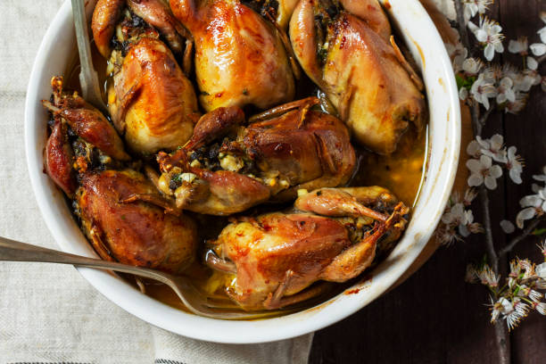 istock Baked quail stuffed with mushrooms, eggs and bread in a ceramic form on a wooden table. 1990804430