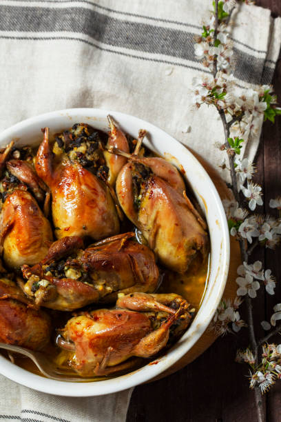 istock Baked quail stuffed with mushrooms, eggs and bread in a ceramic form on a wooden table. 1990804431