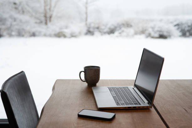 istock Laptop, mobile phone and mug on table when working from home on winter day 1990804435