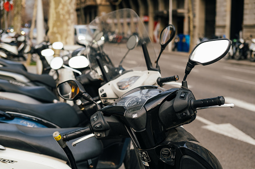 21 February 2023, Spain, Barcelona.  Close up outdoor shot of some motorcycles or mopeds parked on the streets of Barcelona.