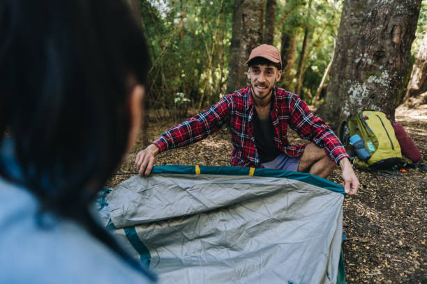 istock Young man setting up tent for camping with friend in the forest 1990832620