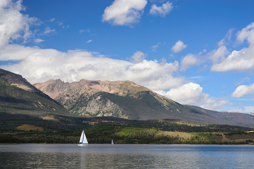 Boats sail across the surface of Dillon Reservoir on a sunny summer day in Colorado.
