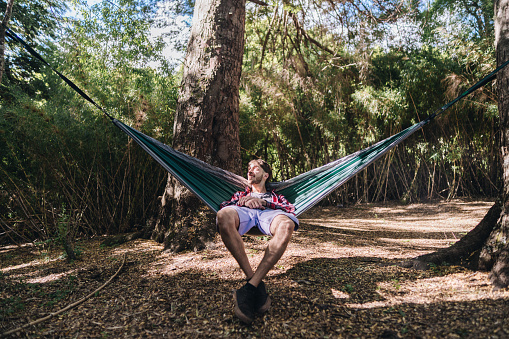 Young man contemplating and resting on a hammock in the forest