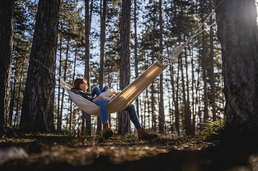 caucasian mother and her daughter small toddler girl in the hammock in nature in winter or spring sunny day relax and enjoy