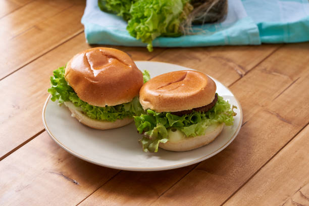 Delicious hamburger with green salad on a wooden table.