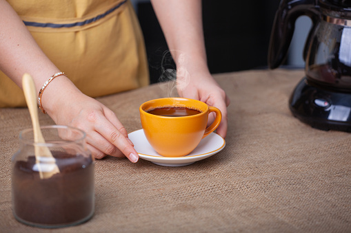 Barista serving cup of fresh coffee with a steamy