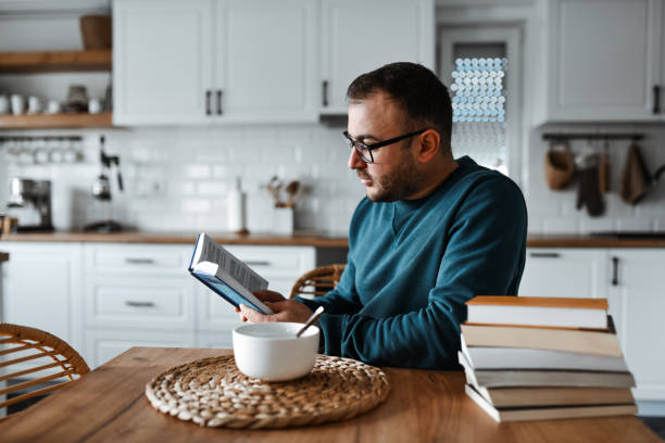 istock Male Reading A Book Or Two In Between Spoonful Of Breakfast Cereal 1990916603