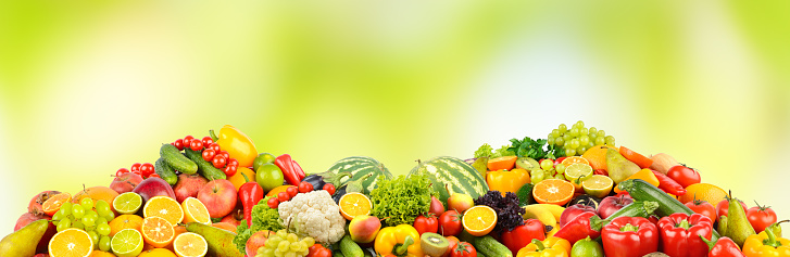 Large collection of fruits and vegetables on green background.