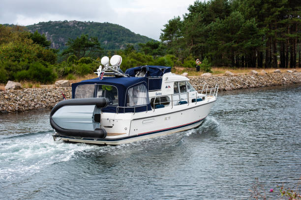 Lindesnes, Norway - July 21 2019: Cabin cruiser passing through a canal.