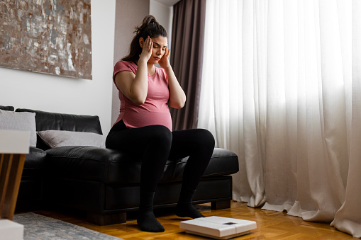 Pregnant woman weighing herself on a scale