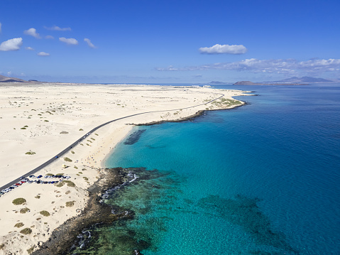 high aspect aerial view of the coast road in the North of Fuerteventura looking towards Corralejo in the sand dunes of the Parque Natural passing playa del moro and grandes playa Canary Islands, Spain