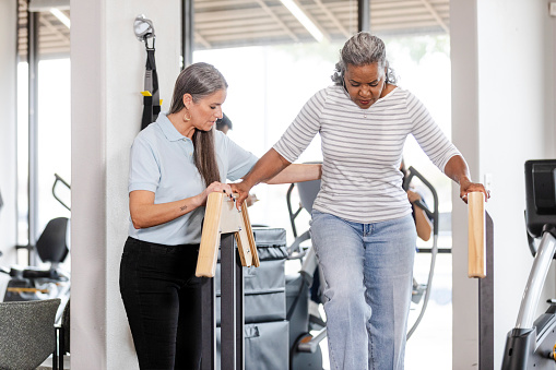 As she recovers from surgery, the mature female patient carefully walks down the stairs at the clinic.