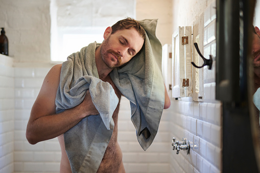 Man, shower and towel dry in bathroom for hygiene, washing and grooming to refresh for skincare and relax. Young guy, happy and clean body for morning beauty treatment, calm and cloth for haircare