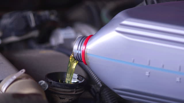 Pouring Filling the Engine with New Synthetic Oil during Car Periodic Maintenance in the Repair Shop