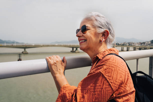 istock Mature woman smiling while looking at the view from Hercilio Luz bridge in Florianopolis, Brazil 1991117358
