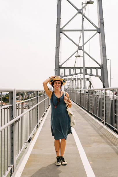 istock Young woman smiling while standing on Hercilio Luz bridge, in Florianopolis, Brazil 1991119459