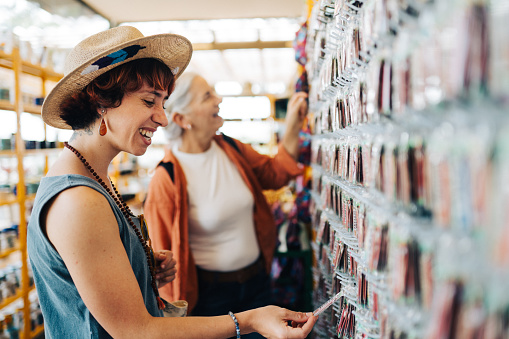 Laughing woman and her mature mother browsing novelty license plates hanging on display in a market stall while shopping for vacation souvenirs