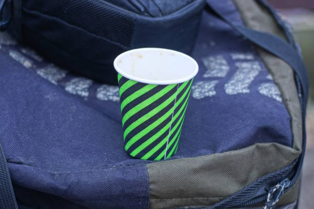 one striped paper glass stands on a black bag on the street