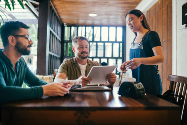 istock Gay couple ordering from a waitress in a restaurant 1991161765