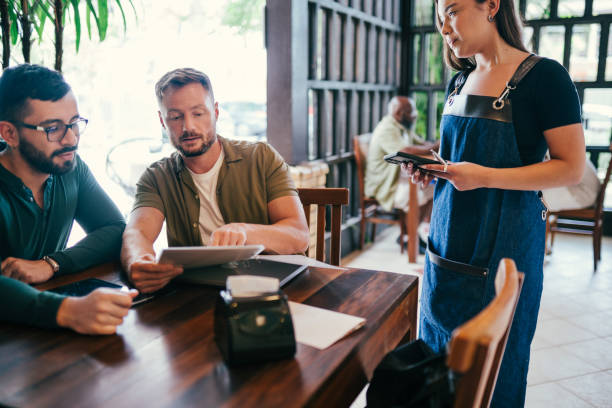 istock Gay couple ordering from a waitress in a restaurant 1991161767