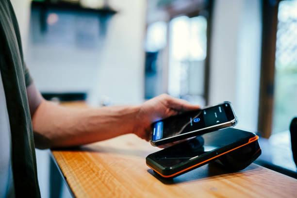 istock Young man paying with cell phone at a coffee shop counter 1991161957