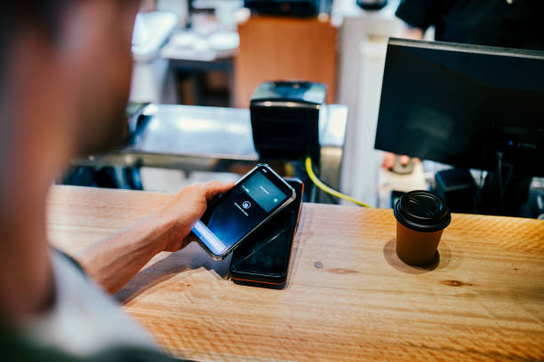 istock Young man paying with cell phone at a coffee shop counter 1991161960