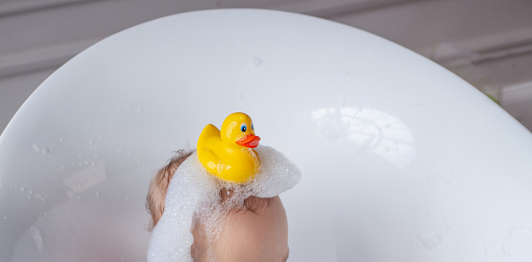 A baby in a bathtub with soap foam.