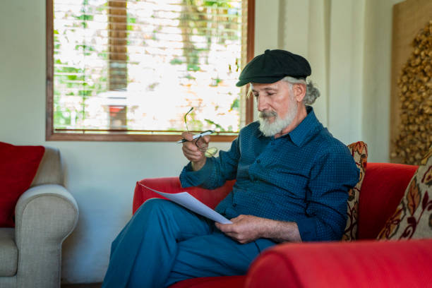 Elderly man of latino ethnicity aged between 70-80 years old is writting a letter at home