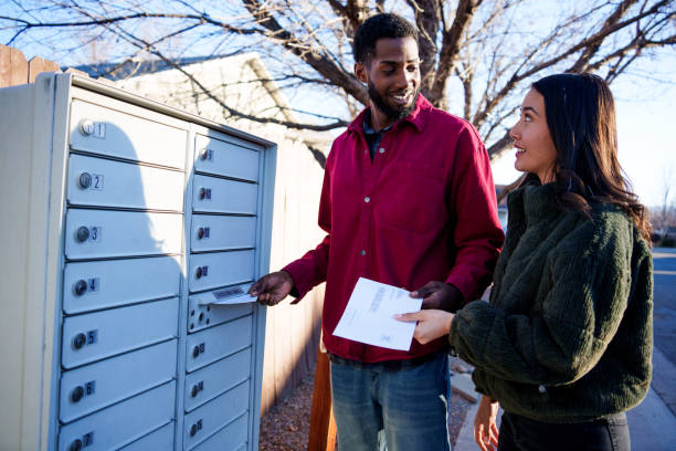 istock Young Mixed-Race Couple Hispanic and African American in Their Twenties Placing Mail-In Ballots Into a Neighborhood Mail Box 1991223708