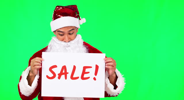 Santa Claus, Christmas and man on green screen with sale sign for holiday, festival and celebration. Studio, festive season and portrait of male person with poster for discount, bargain and deal