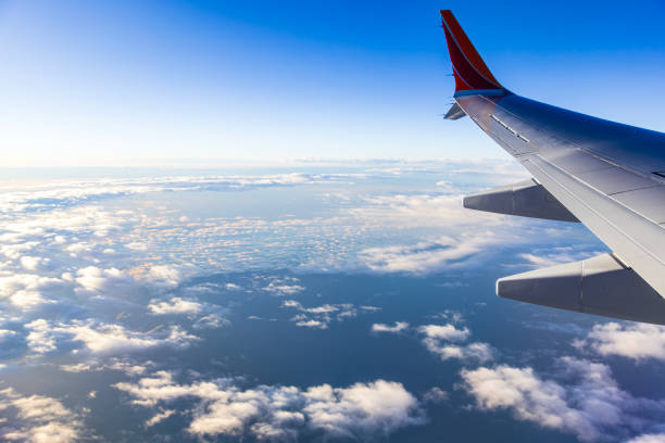 Looking out window of aircraft while flying above the clouds