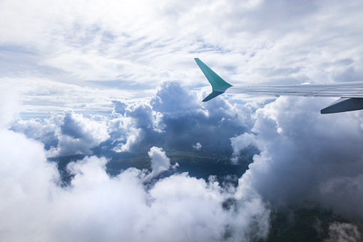 Looking out window of aircraft while flying above the clouds