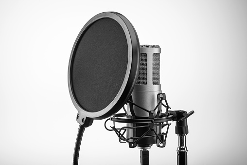 Condenser professional microphone with black pop filter on stand. Audio recording concept.