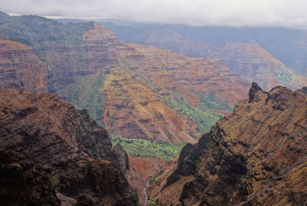The iconic cliffs of the Na Pali Coast rise steeply from the ocean, creating a stunning contrast of vibrant blues and lush greens against rugged rock formations.