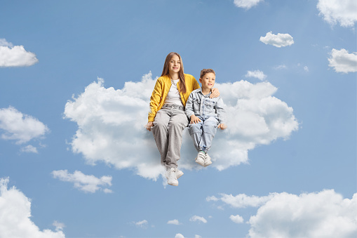 Brother and sister sitting on a cloud up in the sky