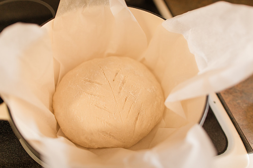 Kneaded dough on a rolling plate with spilled wheat flour. Hands of woman with roller