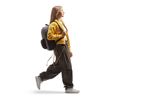 Female teenage student with a backpack walking isolated on white background