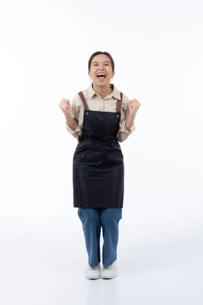 Portrait young asian barista woman wearing apron standing and smile isolated white background, waitress or entrepreneur cheerful, small business or startup, waiter of cafe or coffee shop. stock photo