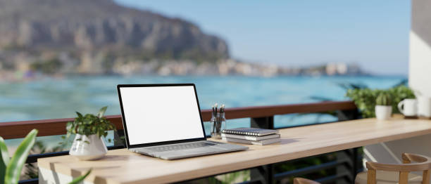 istock A remote workplace with a laptop mockup on a table on a balcony with a beautiful ocean sea view. 1991448932
