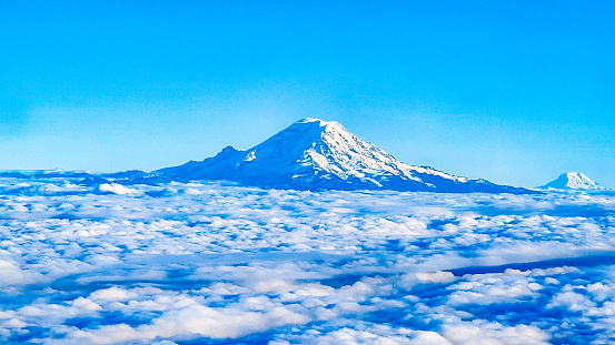 Volcano, Mount Rainier's snow capped peak stands above the clouds in USA of North America.