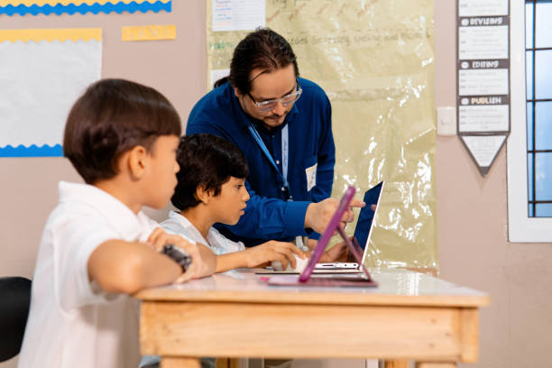 istock Professor male teaching a children to use computers. 1991530011
