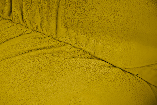 Classic golden yellow leather upholstery leather lounging sofa showing fine dimpled texture pattern background.