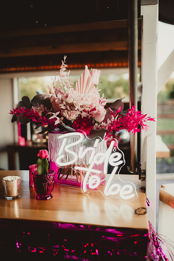Pink bride to be sign and flowers on a bar top