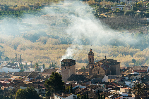 Smoke billows over a scenic hillside town
