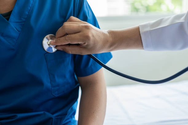 Male doctor caring for a patient holding a stethoscope listening to the patient during a home visit Doctor doing heart check examining man with heart disease, heart disease concept. Close-up image médico masculino que cuida a un paciente que sostiene un estetoscopio escuchando al paciente durante una visita domiciliaria médico que hace un chequeo cardíaco examinando al hombre con enfermedad cardíaca, concepto de enfermedad cardíaca. imagen en p