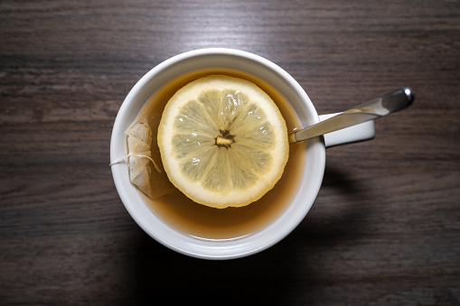 Healthy treatment honey tea with lemon slices on a wooden table