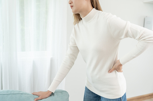 woman holding her lower back while and suffer from unbearable pain health and problems, chronic back pain, backache in office syndrome, scoliosis, herniated disc, muscle inflammation